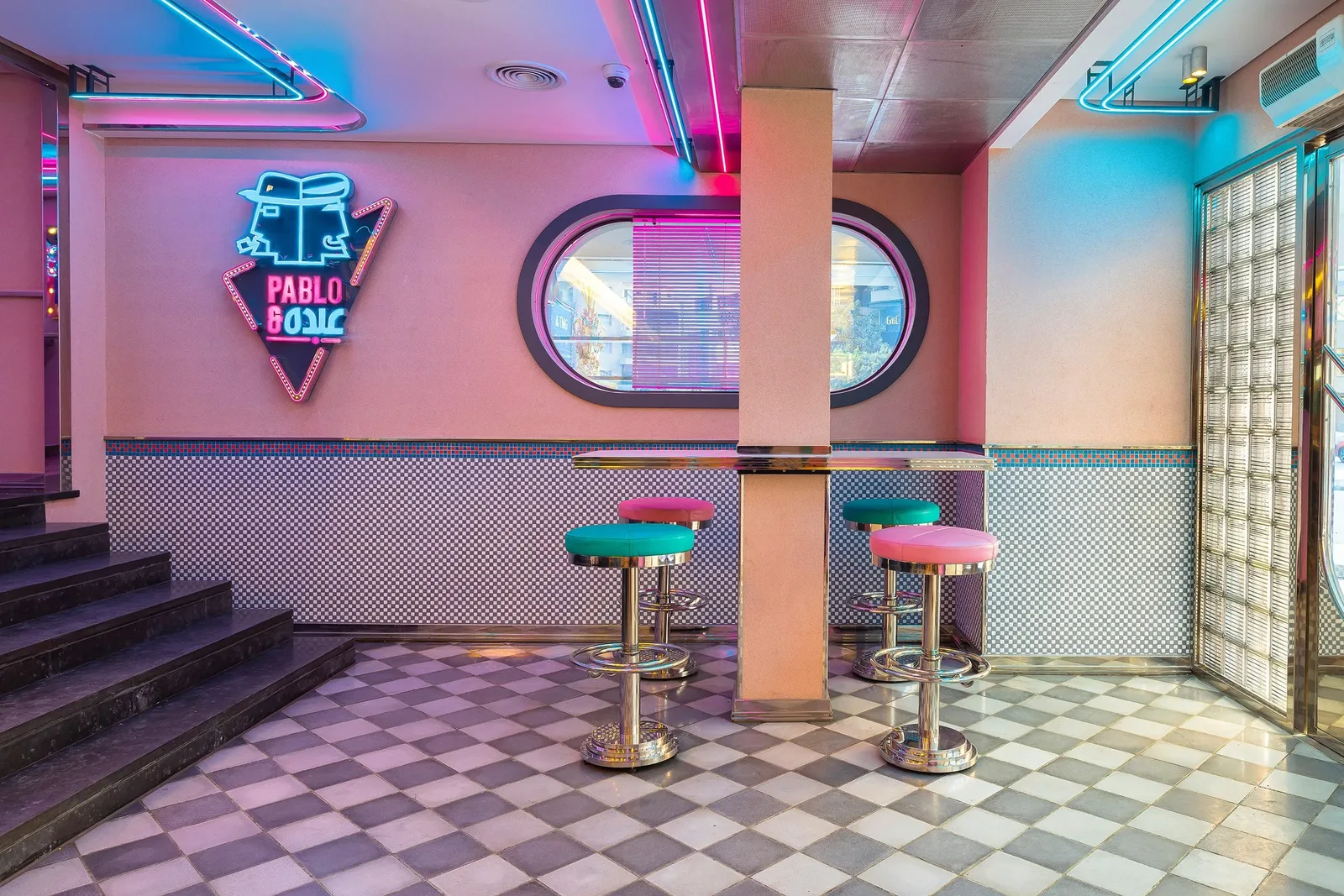 Pablo & Abdo — Neon logo wall with stools in blue and pink
