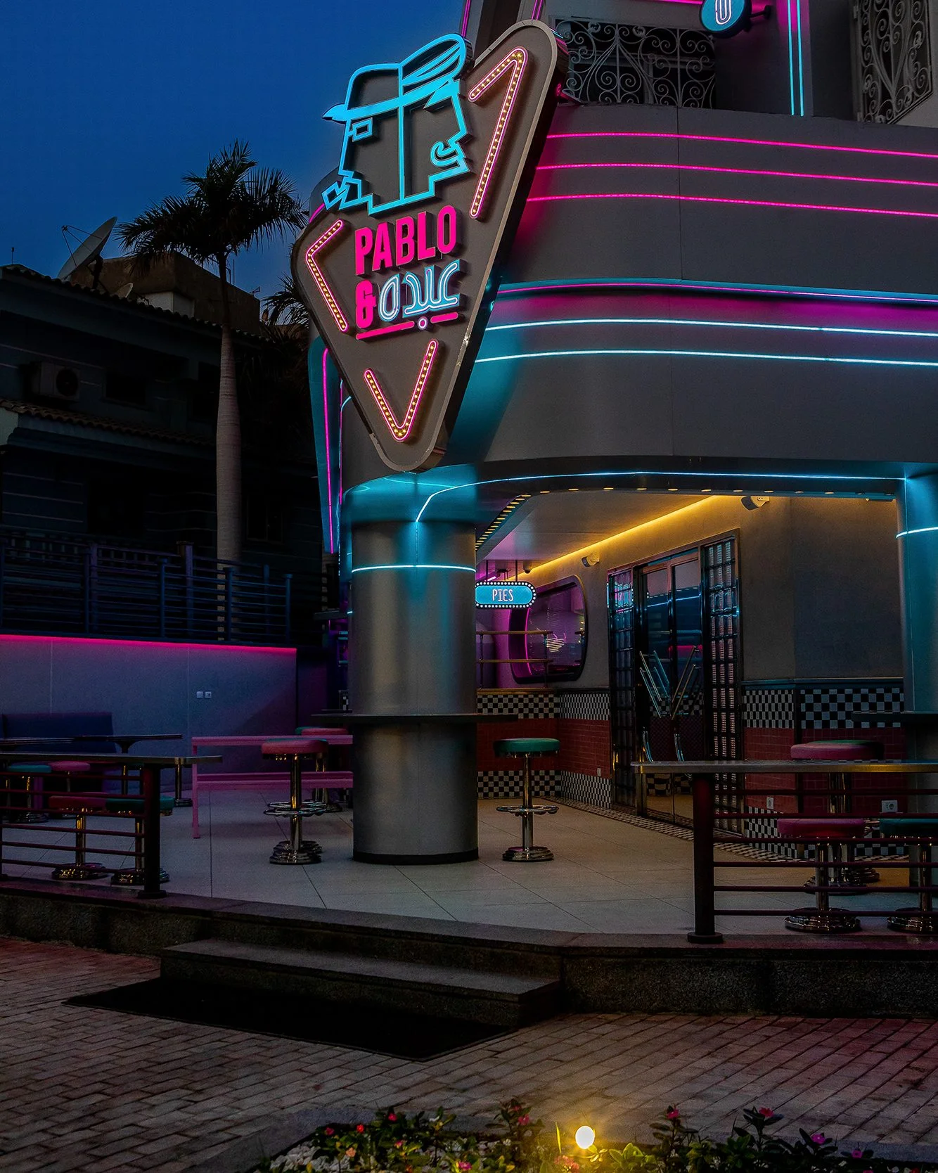 Pablo & Abdo — Entrance beneath the neon sign at night