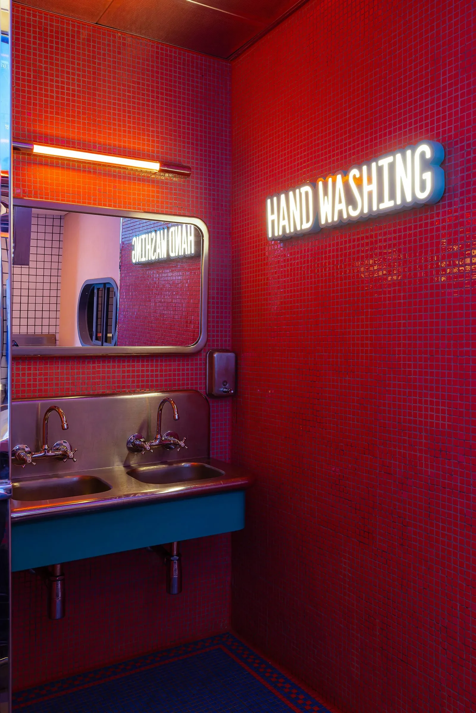 Pablo & Abdo — Washroom in red tiles with neon sign