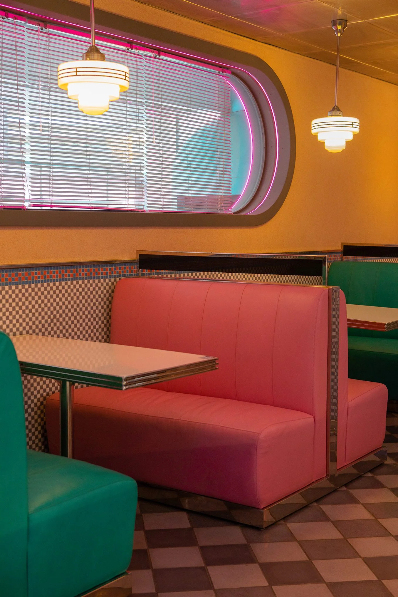 Pablo & Abdo — Strawberry-pink leather booth beneath a porthole window